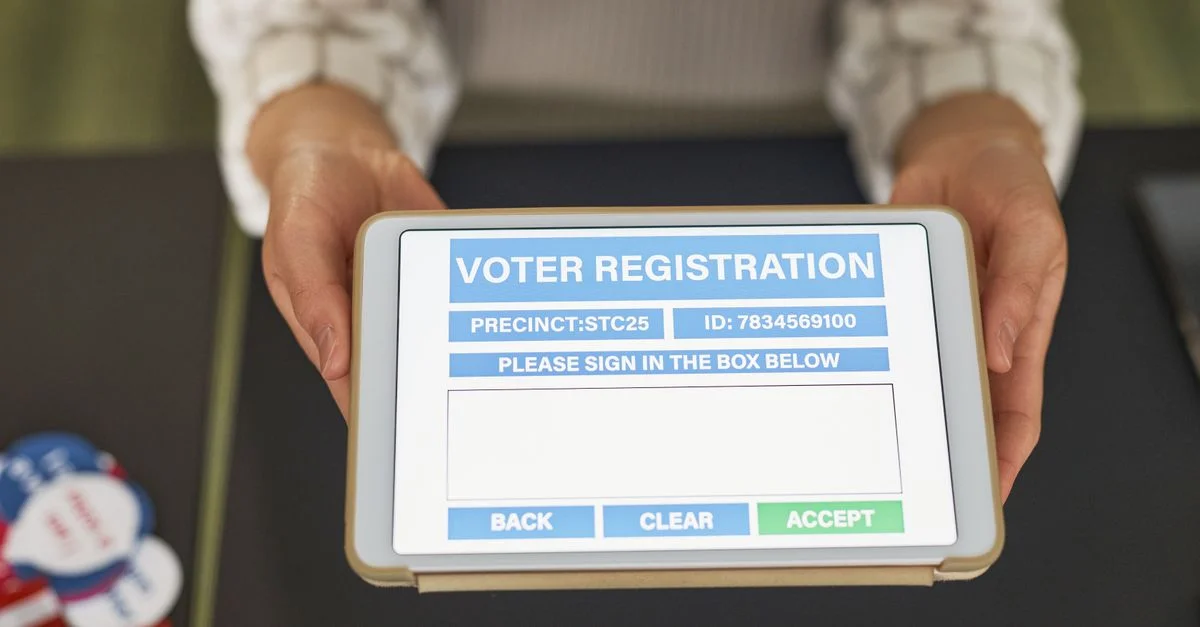 Gros plan de mains tenant une tablette affichant un formulaire d'inscription des électeurs numérique.