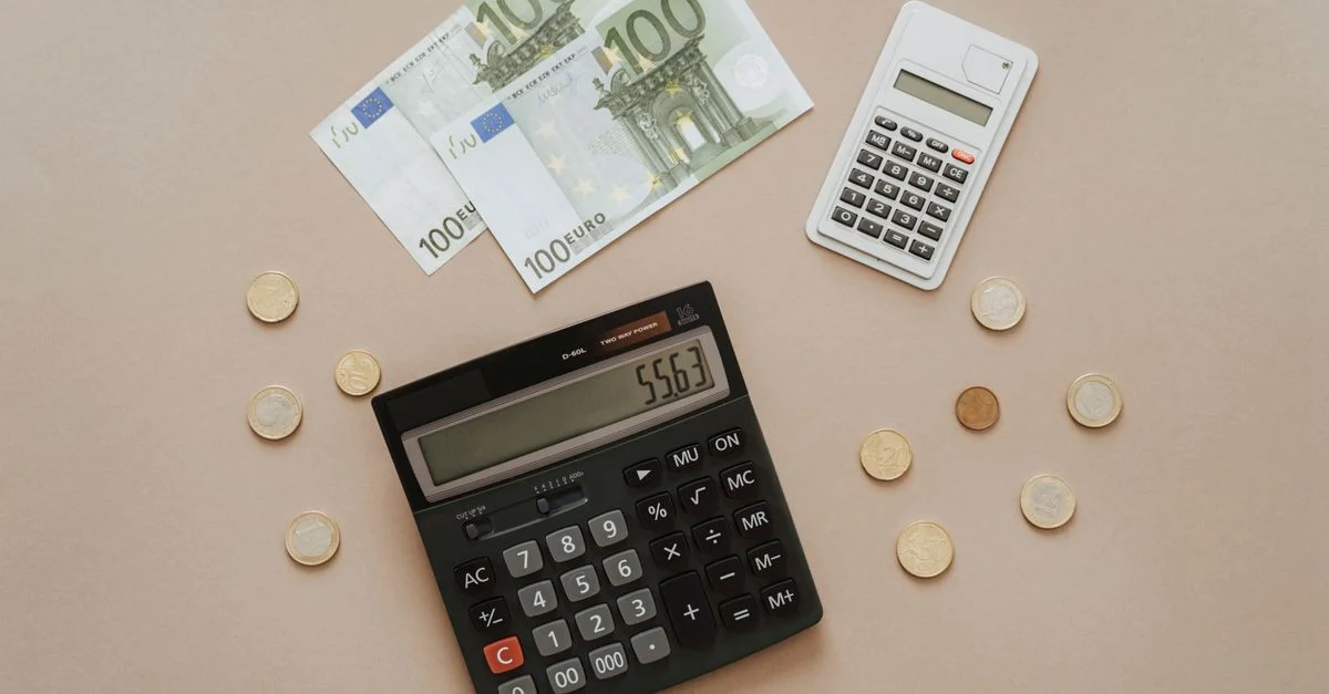 Vue de dessus de calculatrices et de la monnaie Euro, illustrant les calculs financiers et la gestion de budget.