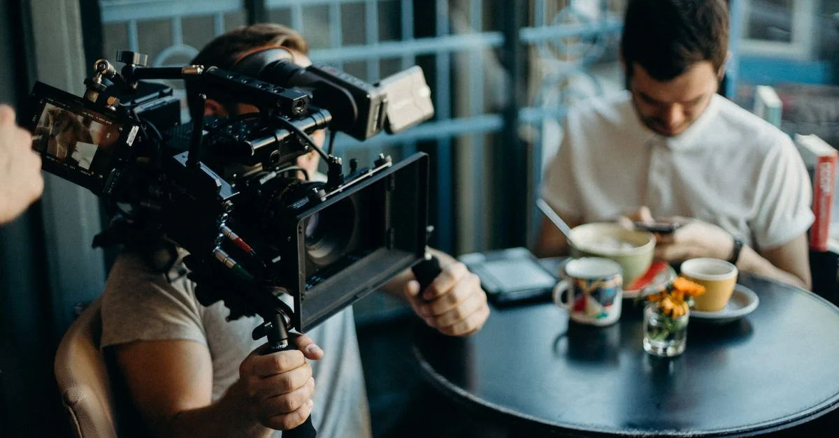 Un caméraman filme une scène dans un café confortable, capturant l'atmosphère cinématographique.