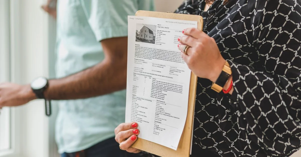 Agent immobilier tenant des documents de propriété sur un clipboard dans un bureau.