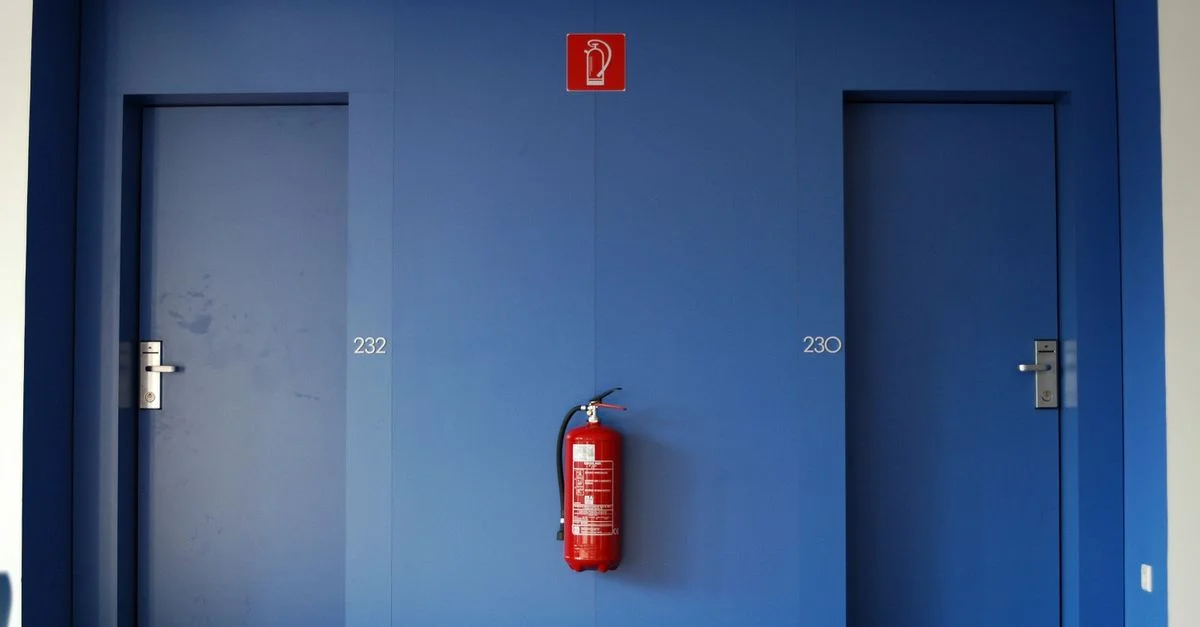 Portes bleues dans un couloir avec un extincteur rouge entre elles.