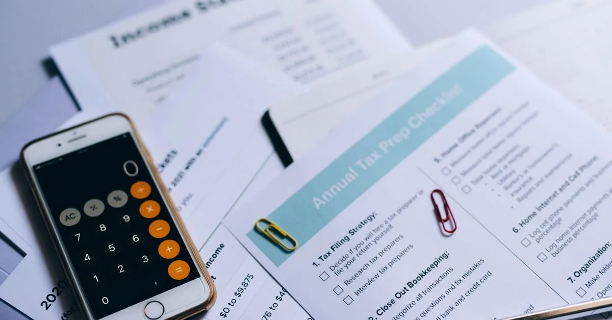 Configuration de préparation fiscale avec documents, calculatrice sur smartphone et liste de contrôle.