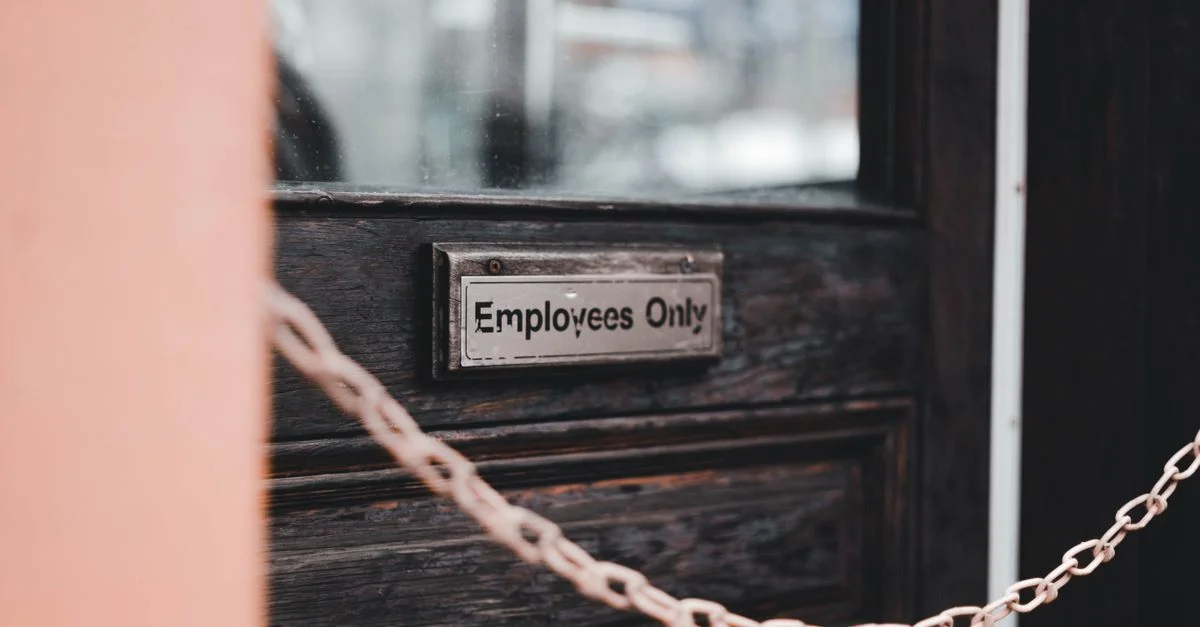 Gros plan sur un panneau 'Réservé aux Employés' sur une porte en bois rustique sécurisée par une chaîne.