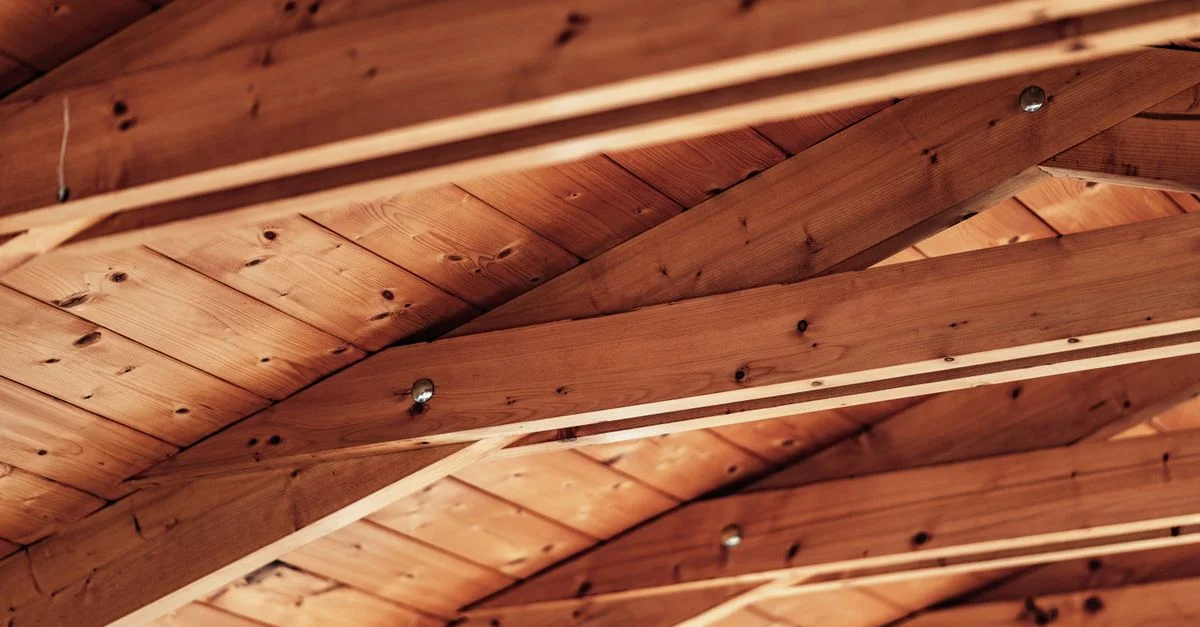 Gros plan d'un plafond en bois rustique avec des poutres apparentes et une texture de bois naturel.