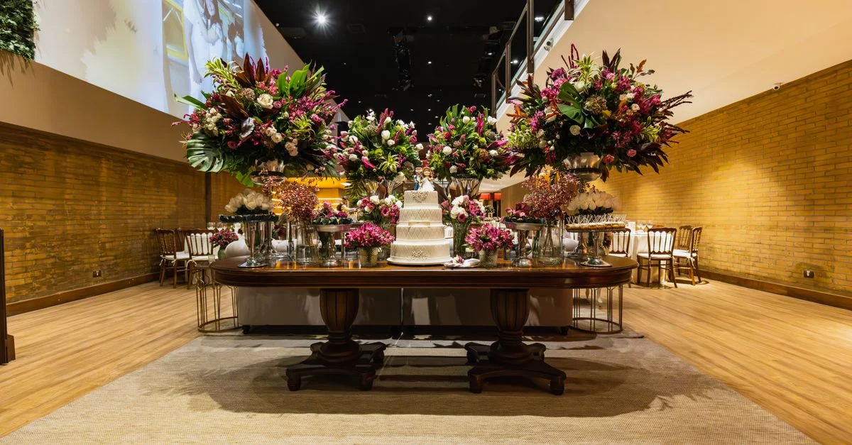 Table de réception de mariage luxueuse décorée de fleurs et d'un gâteau à l'intérieur.