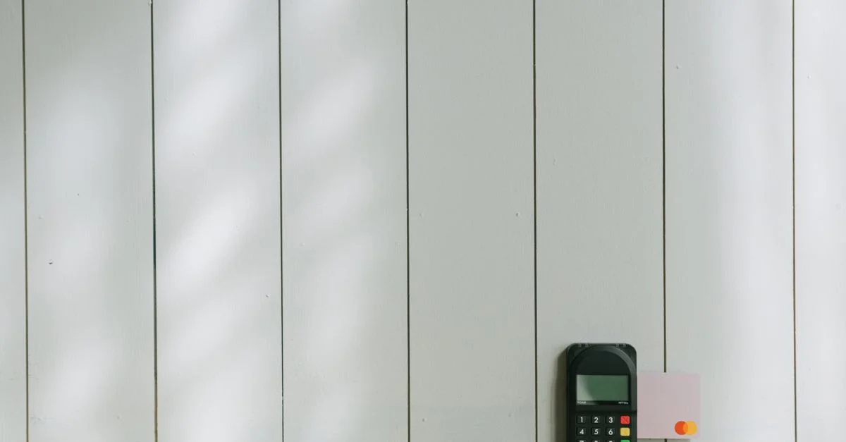 Un terminal de paiement élégant avec une carte insérée sur un fond en bois clair, mettant en avant la technologie du commerce moderne.