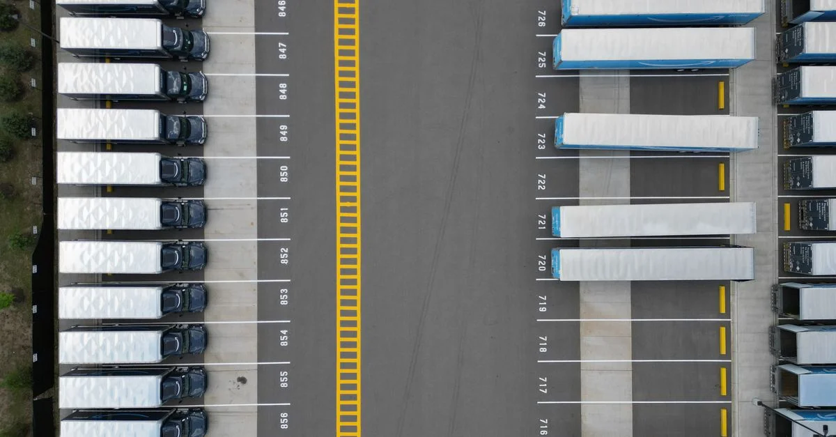 Vue de haut des camions alignés dans un parking logistique, montrant un hub de transport organisé.