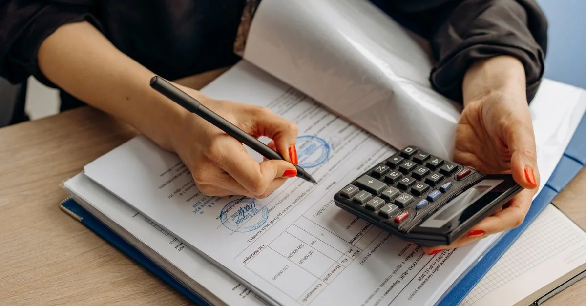Un comptable utilisant une calculatrice et signant des documents, mettant en avant l'analyse financière.