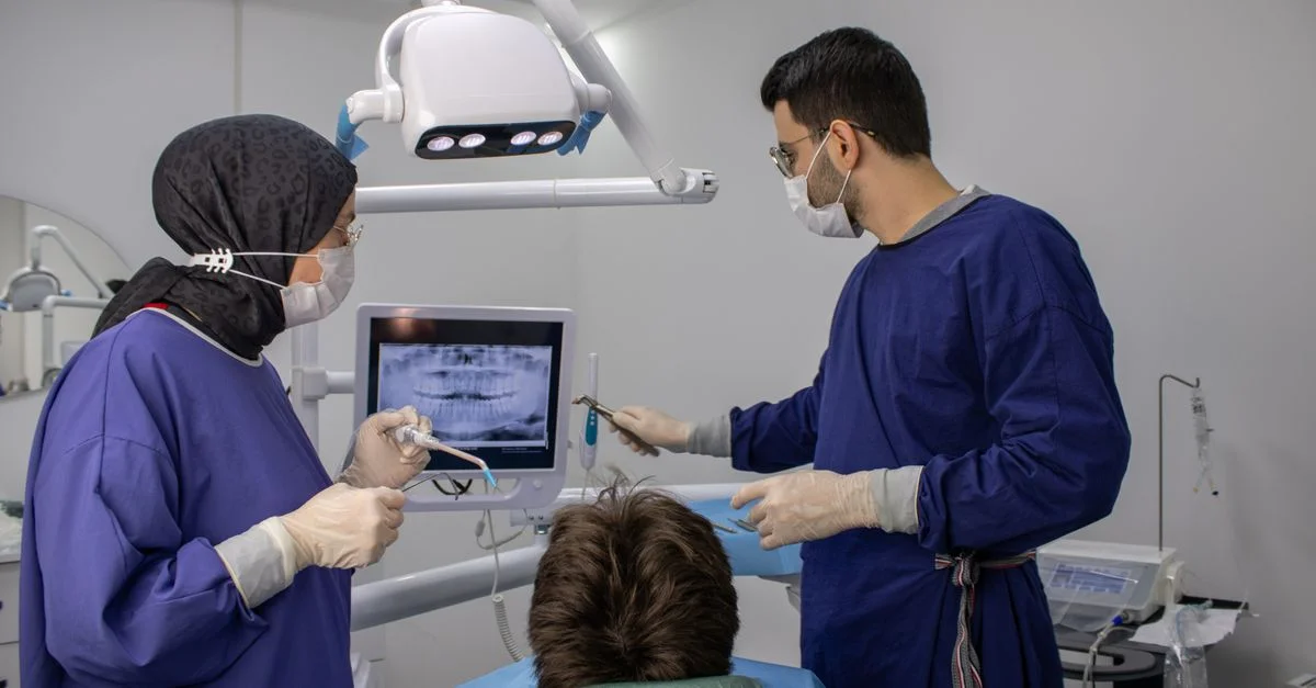 Dentistes et patient lors d'un examen dentaire dans une clinique moderne, axé sur l'hygiène bucco-dentaire.