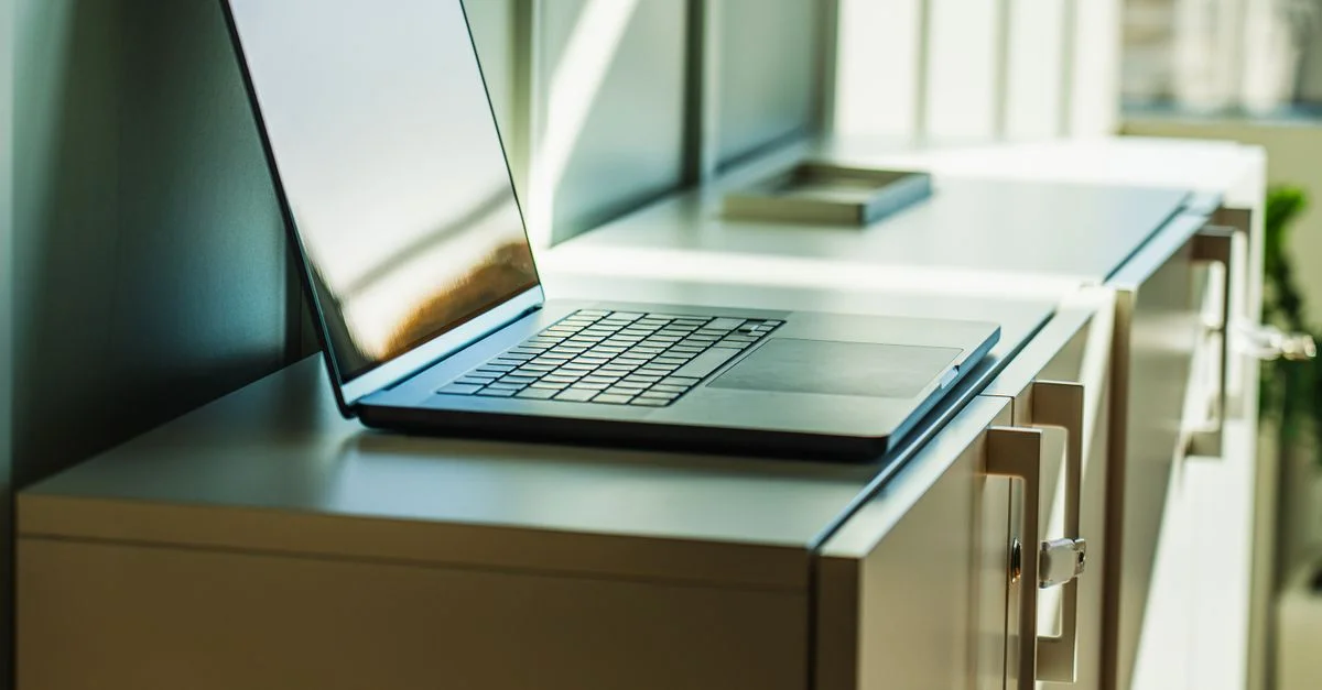 Un ordinateur portable sur une armoire de bureau ensoleillée, idéal pour les contextes professionnels ou d'entreprise.