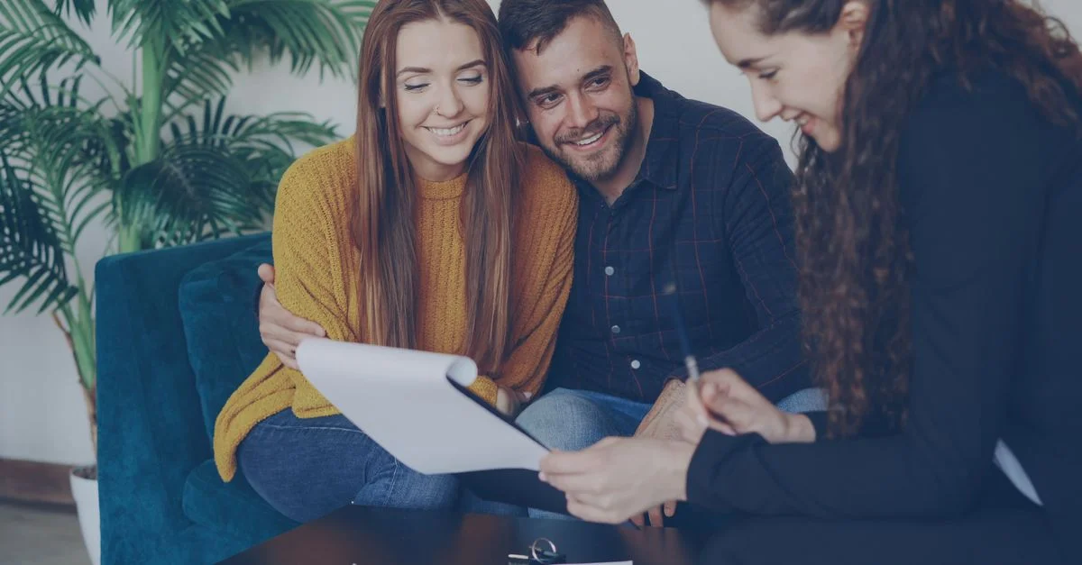Un couple heureux discute de ses finances avec son conseiller dans un bureau confortable.