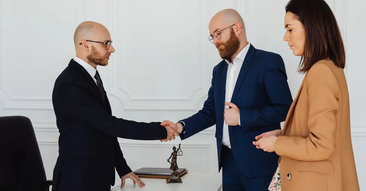 Trois professionnels en affaires en tenue formelle se serrent la main lors d'une réunion de bureau.