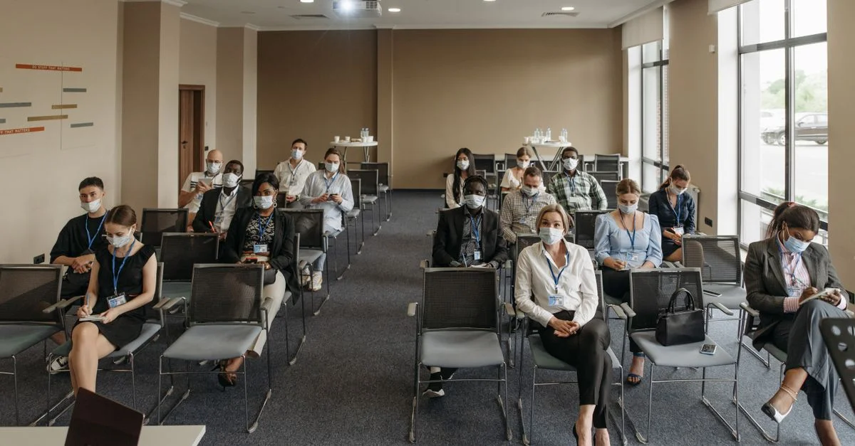 Participants portant des masques dans un agencement respectant la distanciation sociale lors d'une réunion d'affaires pour garantir la sécurité.