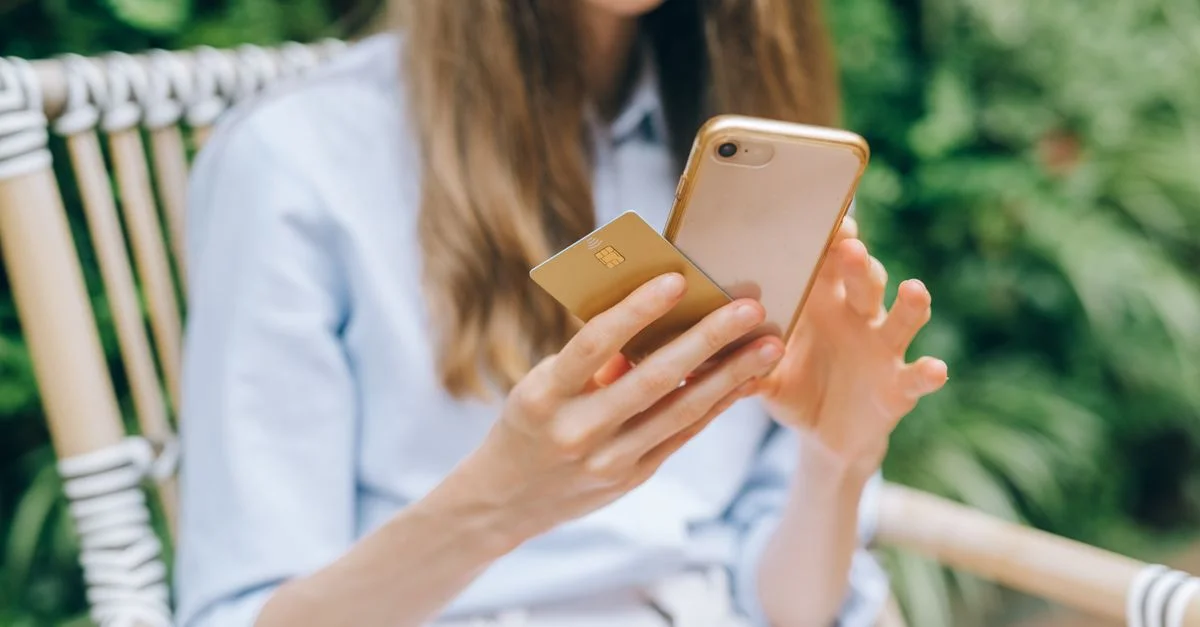 Une femme effectuant un achat en ligne avec un smartphone et une carte de crédit en plein air.