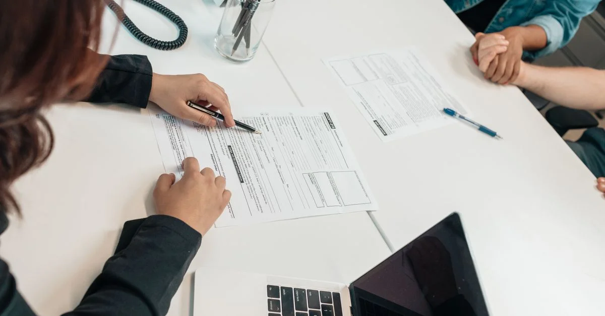 Une réunion professionnelle avec signature de document à un bureau, axée sur le travail d'équipe.