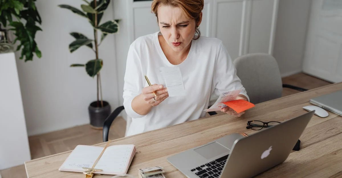 Femme examinant des documents à un bureau, travaillant intensément dans un cadre moderne de bureau à domicile.
