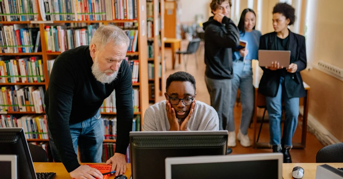 Des étudiants et un mentor collaborent dans une bibliothèque universitaire, participant à des activités éducatives.