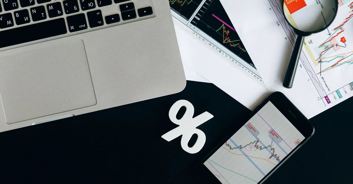 Vue de dessus des outils d'analyse financière avec ordinateur portable, smartphone et graphiques sur un bureau.