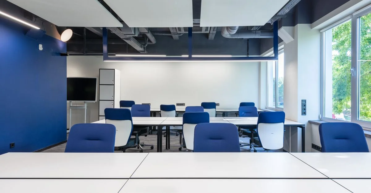 Intérieur de bureau contemporain avec des chaises bleues et des bureaux blancs, idéal pour un usage corporate.