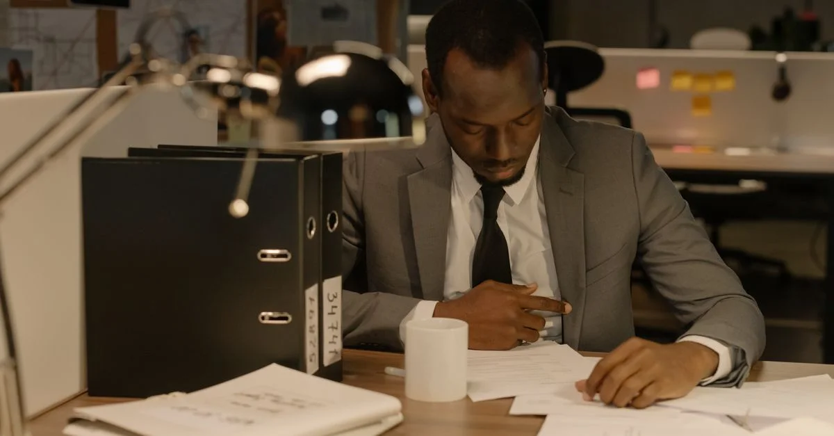 Homme d'affaires concentré sur des documents à son bureau dans un cadre de bureau moderne.