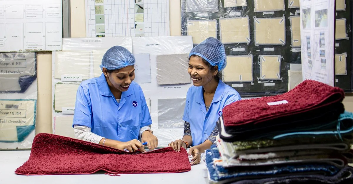 Deux ouvrières du textile inspectent les tissus avec des expressions joyeuses dans une usine.
