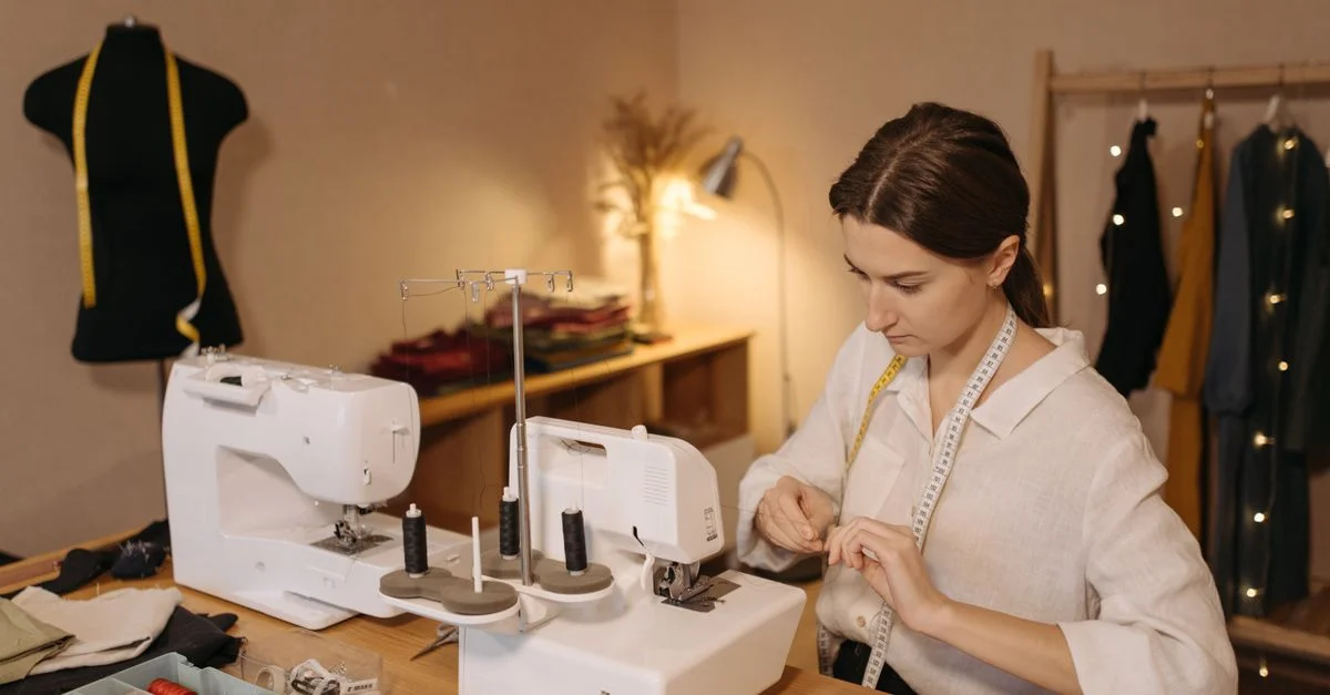 Femme caucasienne enfilant une machine à coudre dans un atelier de mode. Environnement créatif et concentré.