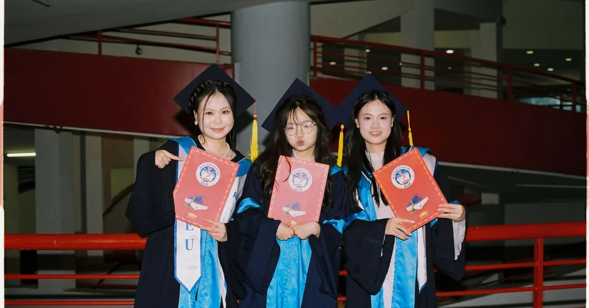 Trois diplômés en toque et en robe de cérémonie brandissent fièrement leurs diplômes à l'intérieur, marquant une étape importante.