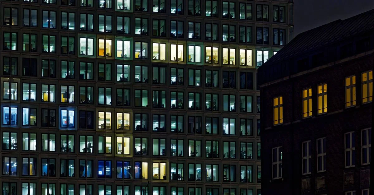 Façade d'immeuble de bureau illuminée avec des fenêtres scintillantes la nuit.