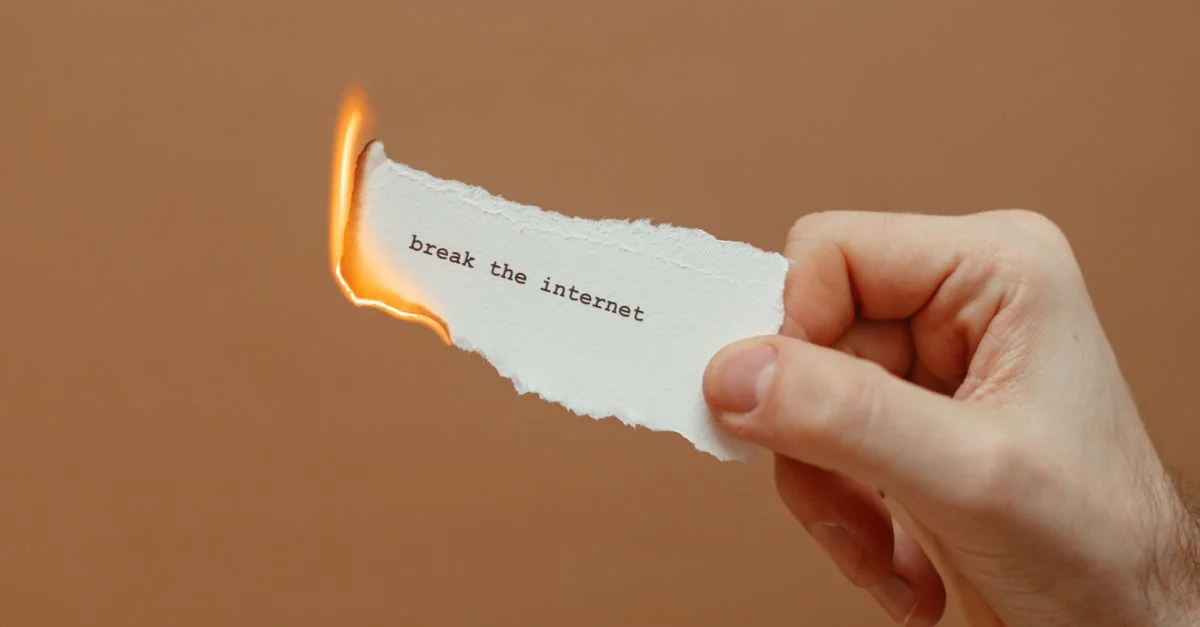 Gros plan sur une main tenant un papier brûlant avec le texte 'briser internet'.