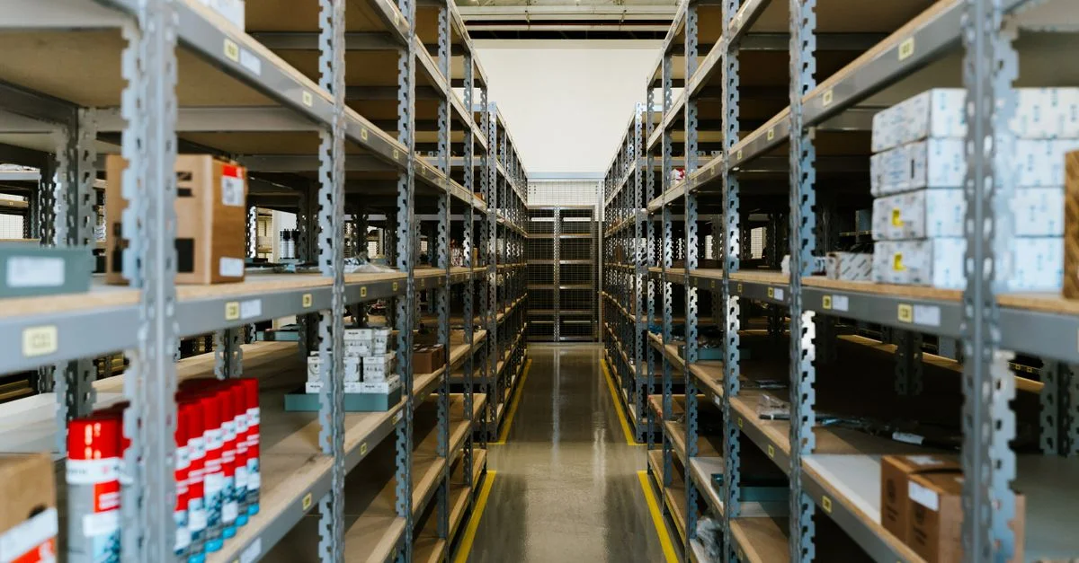 Vue large d'un entrepôt industriel organisé avec des étagères métalliques et des marchandises entreposées.