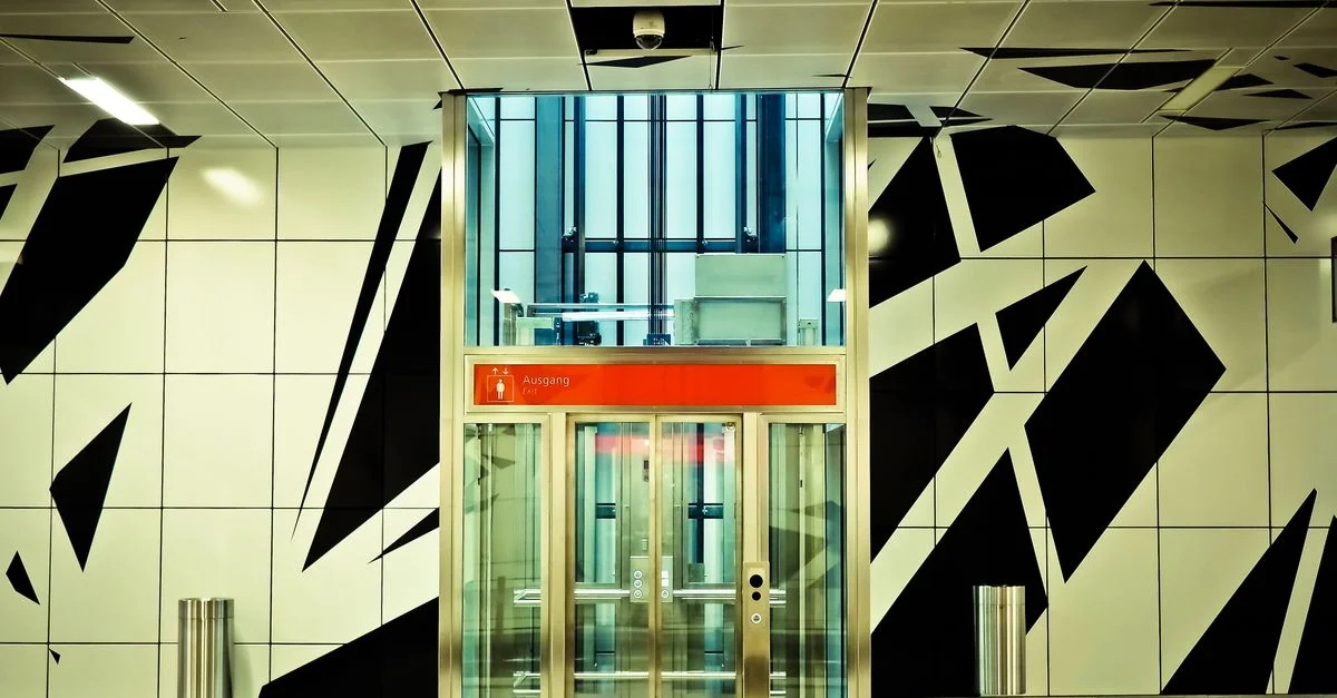 Une entrée de station de métro moderne et vibrante avec des motifs géométriques et des ascenseurs en verre.