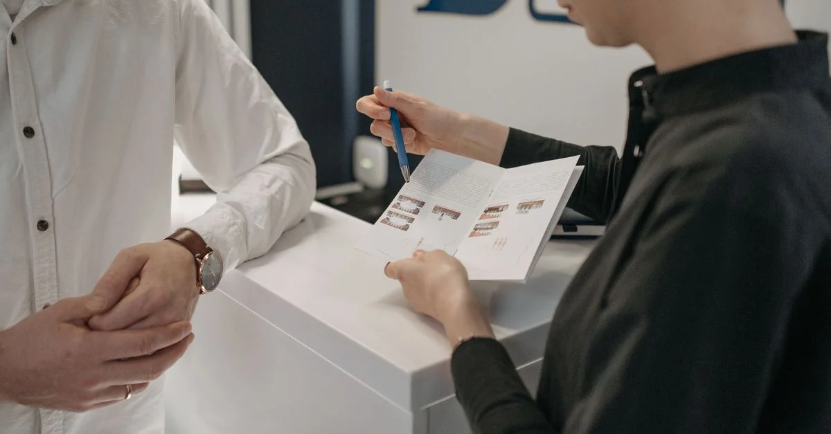 Le personnel de réception explique des informations à un client au comptoir de la clinique.