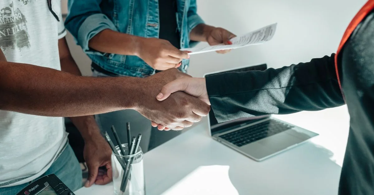 Deux professionnels en affaires établissant un accord par poignée de main dans un environnement de bureau moderne avec des documents.