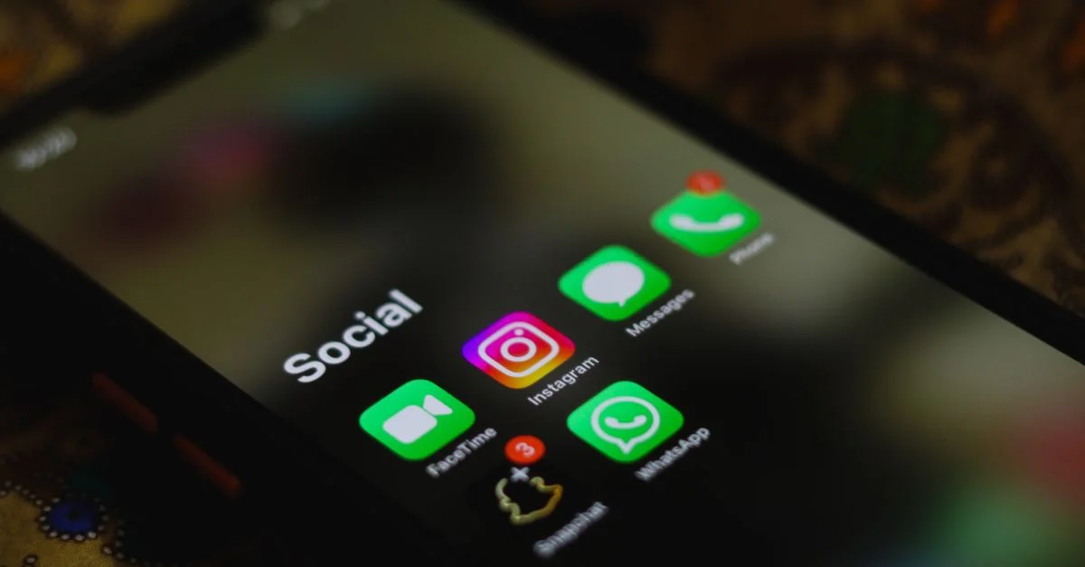 Gros plan d'un smartphone affichant des icônes d'applications de réseaux sociaux sur l'écran.
