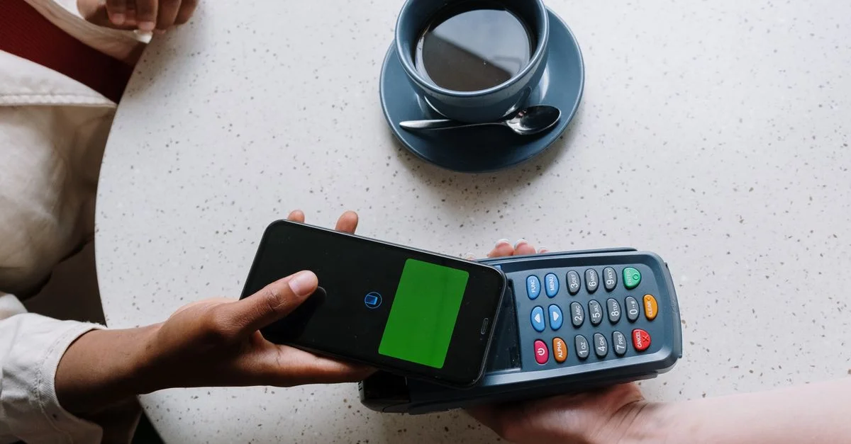 Paiement sans contact avec un smartphone et un lecteur de carte à une table de café.