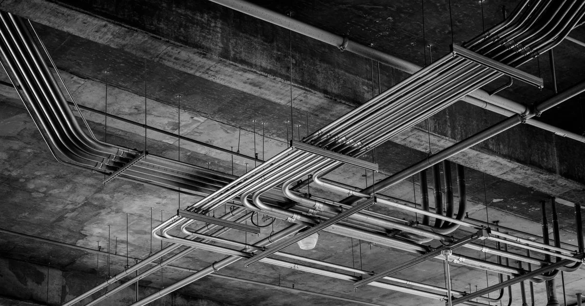 Photo en noir et blanc d'un plafond industriel avec des canalisations métalliques à Boise, ID.