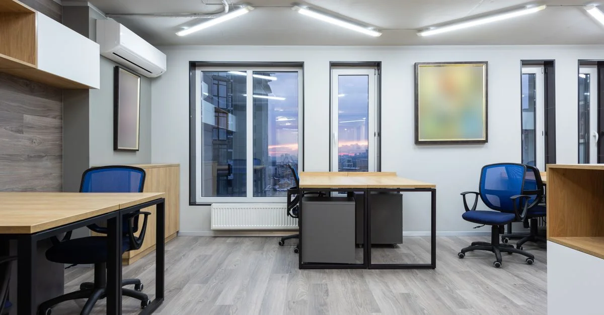 Bureau contemporain avec des chaises bleues, des bureaux en bois et de grandes fenêtres.