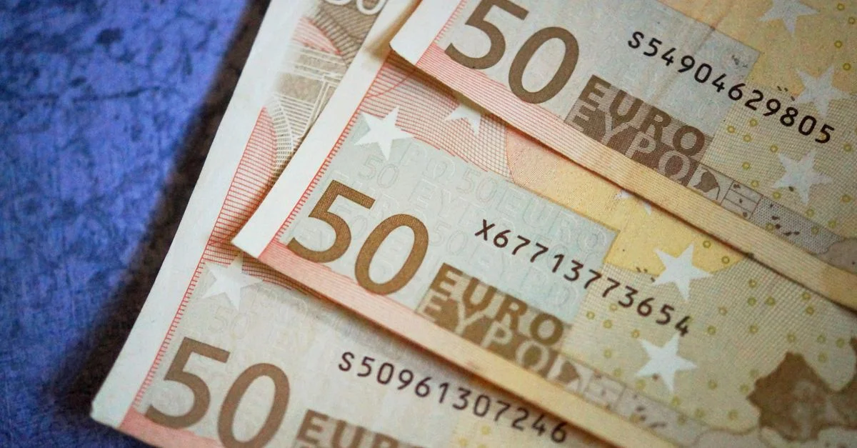 Pile de billets de 50 Euros disposés sur une surface texturée, mettant en avant la devise européenne.