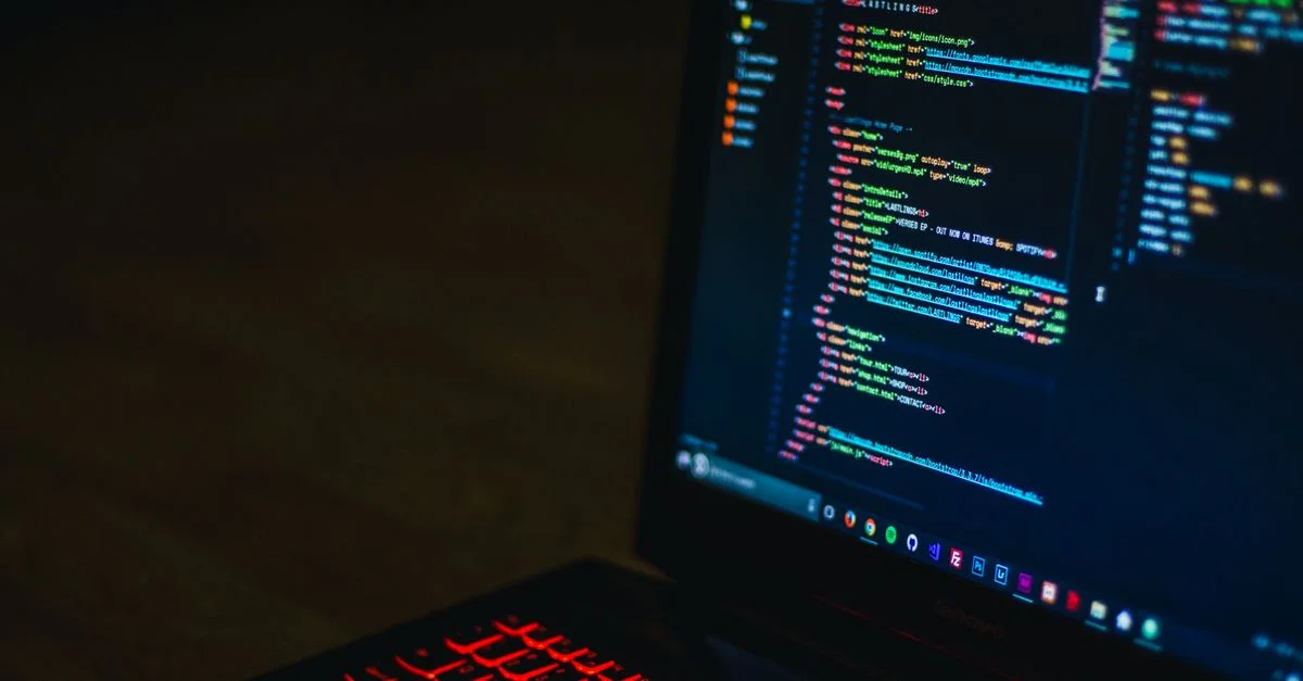 Un clavier rétroéclairé rouge et du code sur l'écran de l'ordinateur portable créent une ambiance technologique.
