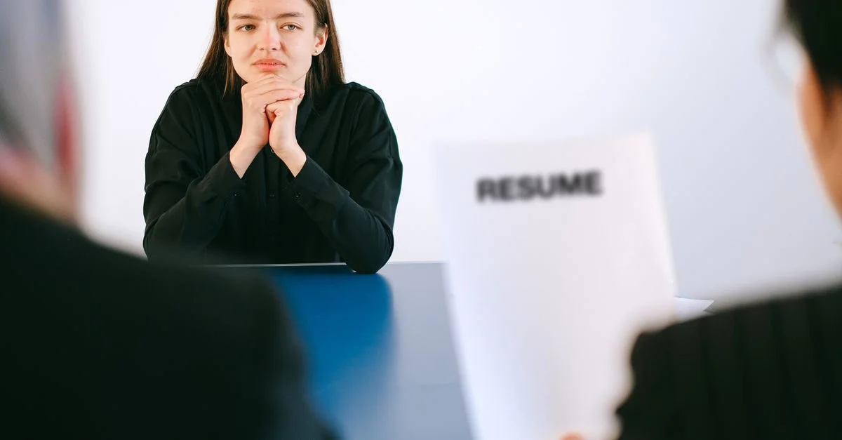 Une femme en entretien d'embauche face à deux employeurs avec un accent sur son CV.