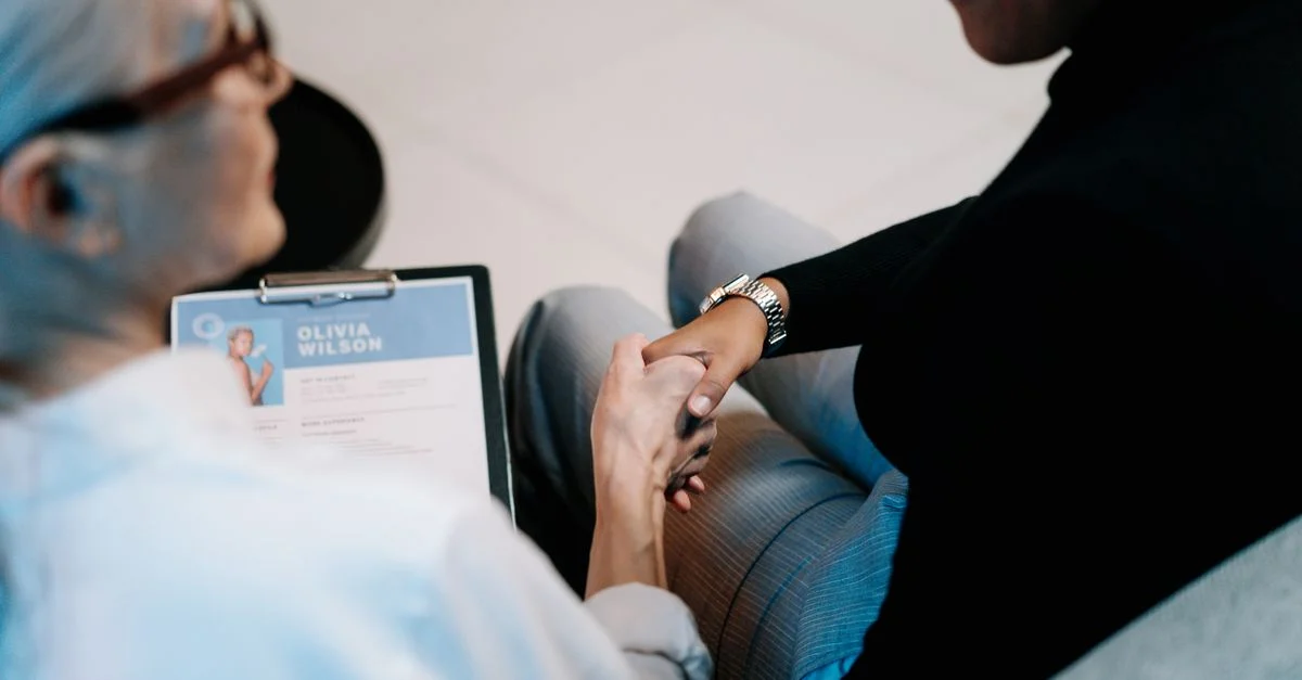 Deux femmes professionnelles se serrant la main dans un environnement de bureau, axées sur le recrutement et la connexion.