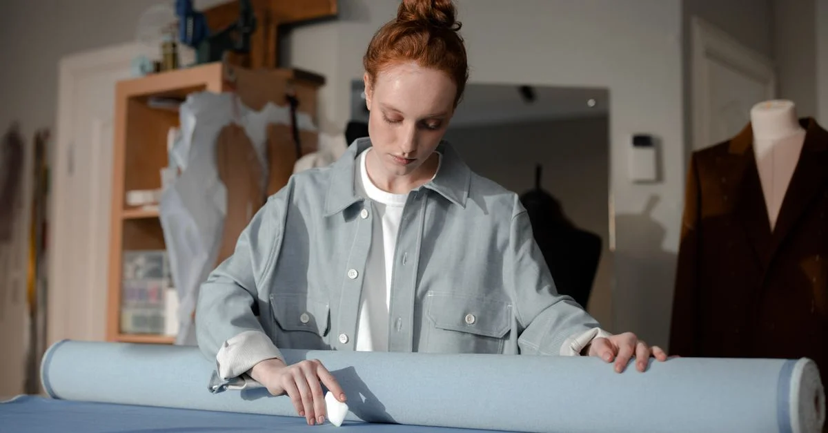 Femme couturière marquant un tissu avec de la craie dans un atelier de mode.