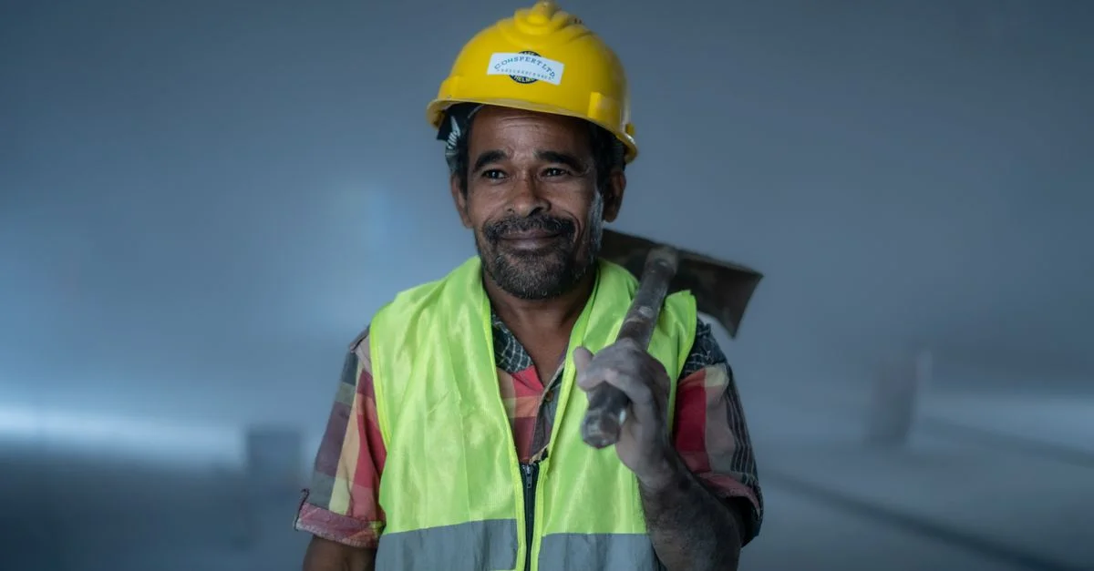 Ouvrier du bâtiment souriant, en tenue de sécurité, tenant un outil à l'intérieur. Thème professionnel et industriel.