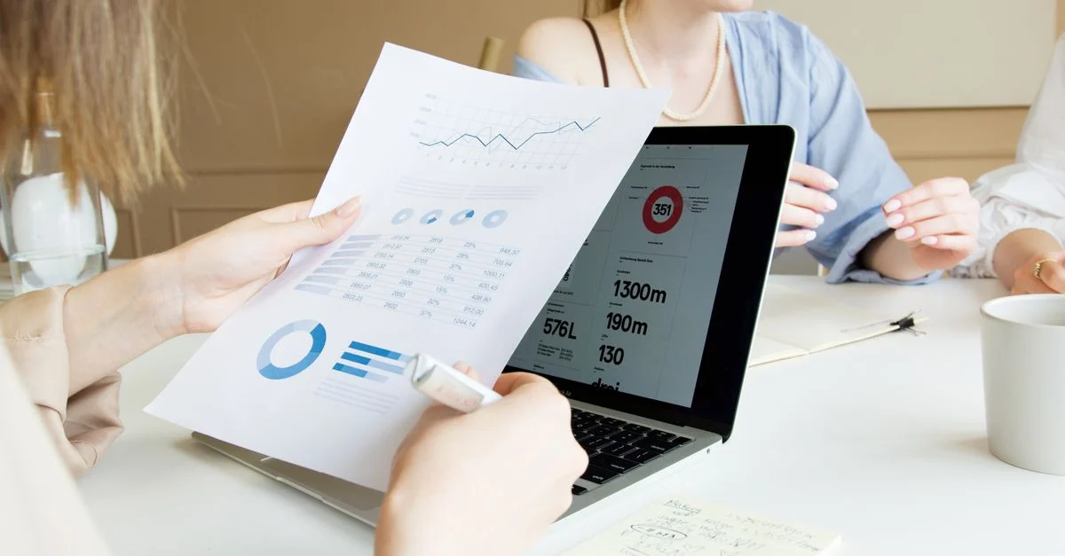 Gros plan de professionnels examinant des graphiques et des données financières sur un ordinateur portable lors d'une réunion.