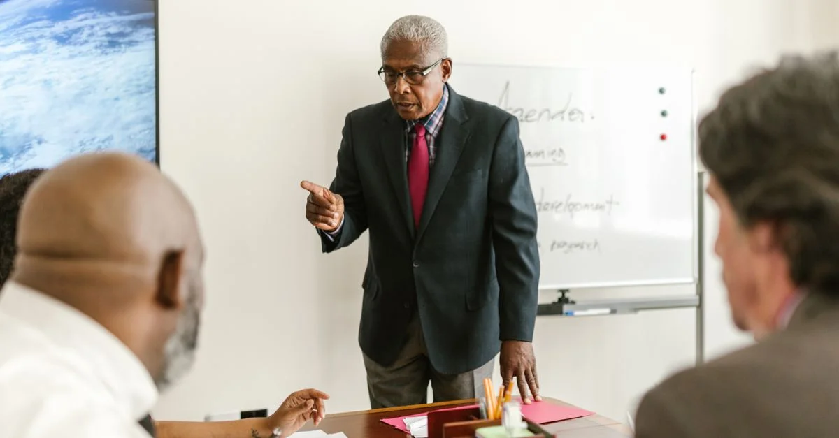 Un homme senior dirige une réunion d'affaires avec des collègues dans un cadre de bureau professionnel.