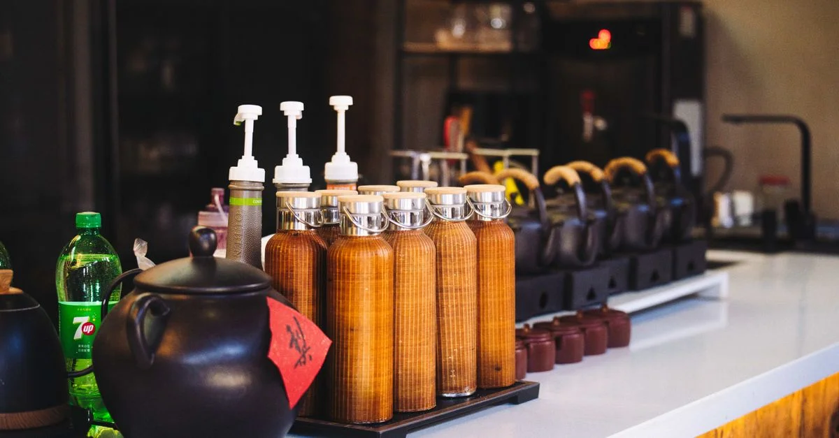 Un élégant comptoir de bar à café avec théières, bouteilles de sirop et distributeurs de boissons.