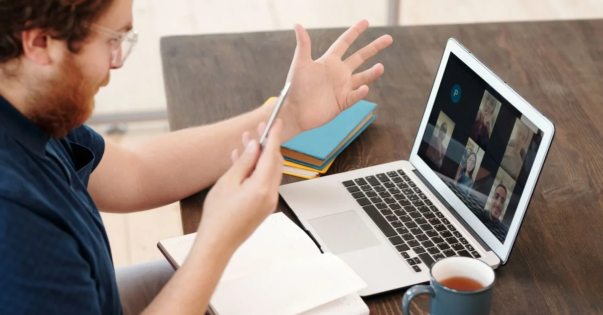 Homme engagé dans une réunion virtuelle à domicile avec un ordinateur portable et du thé, discutant et étudiant en ligne.