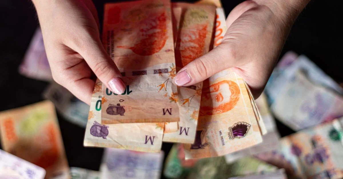 Des mains tenant des billets de pesos argentins, représentant la monnaie et la finance à Buenos Aires, Argentine.