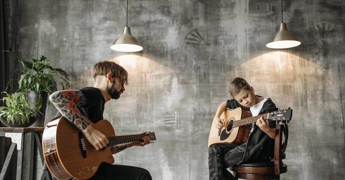 Un enfant et un adulte participent à un cours de guitare acoustique en intérieur avec un fond artistique moderne.