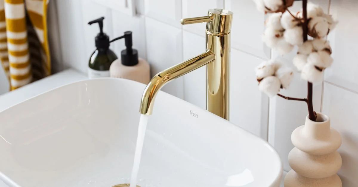 Un lavabo de salle de bain élégant avec un robinet doré moderne et de l'eau qui coule pour une touche de luxe.